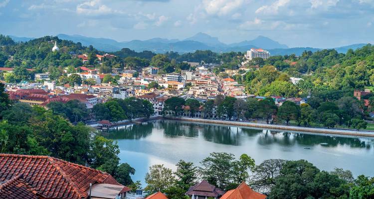 Ville pittoresque au bord du lac entourée de collines boisées avec des montagnes lointaines sous des nuages doux