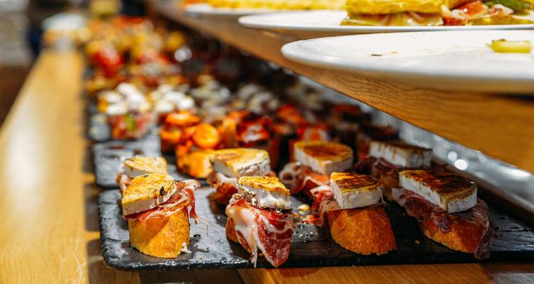 Une variété de délicieux tapas incluant du jambon et du fromage sur un long comptoir.