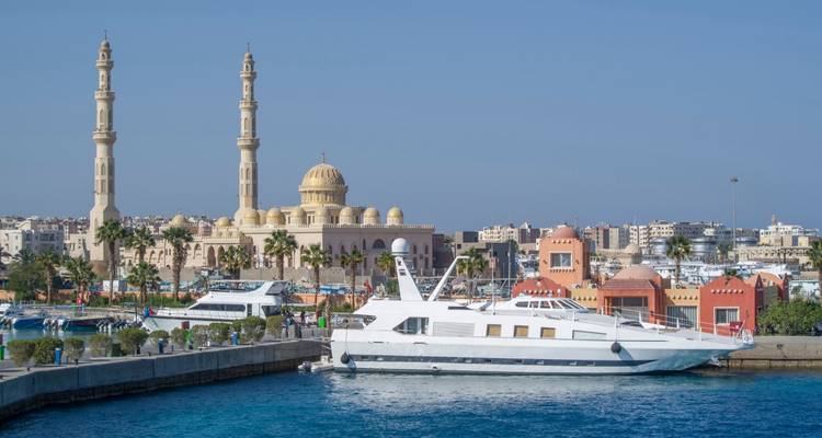 Hurghada’s marina with sleek yachts, turquoise Red Sea waters, and a large mosque dominating the skyline.