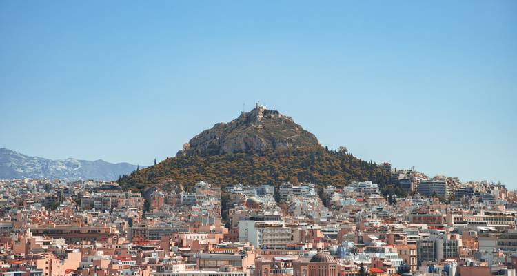 Une vue lointaine de la colline du Lycabette avec le paysage urbain qui l'entoure.