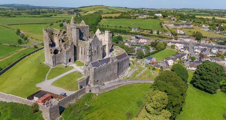 Luchtfoto van de middeleeuwse kathedraalruïnes van Rock of Cashel die het groene Ierse platteland en dorp domineren.