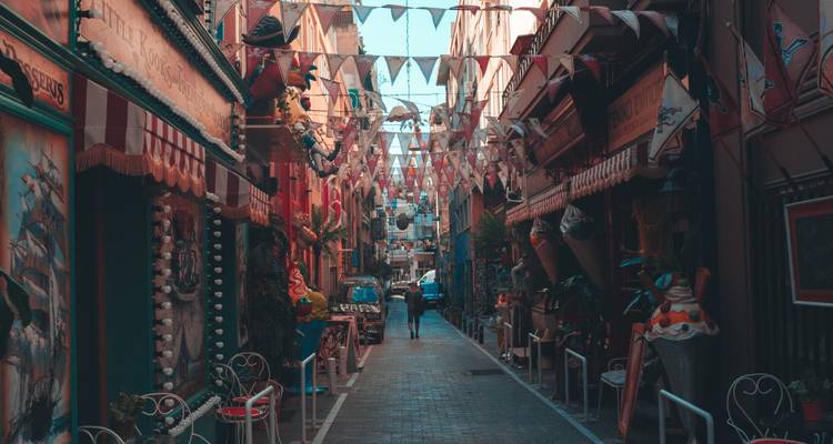 Ruelle étroite avec des drapeaux et une activité animée.