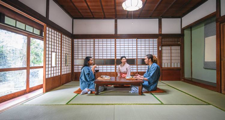 Des personnes assises dans une pièce japonaise traditionnelle en train de prendre un repas.