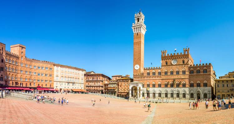 Sunny panorama of Siena’s Piazza del Campo with Torre del Mangia and historic palaces.