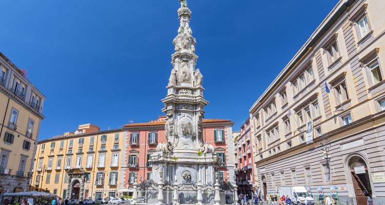Place de ville animée avec colonne historique et bâtiments colorés.