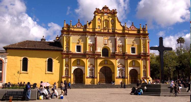 Fachada amarillo brillante de la catedral de San Cristóbal de las Casas que domina la plaza central bullendo de lugareños.