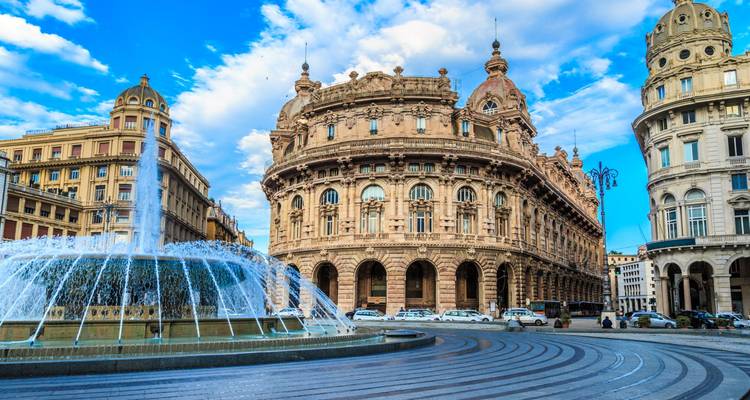 Fountain spraying water in front of ornate historic buildings at Piazza De Ferrari in Genoa.