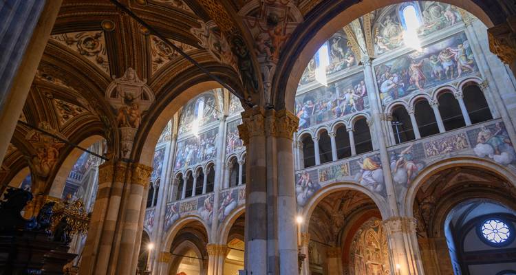 Intérieur somptueux orné de fresques d'une cathédrale italienne avec des arcs élancés et une douce lumière naturelle.