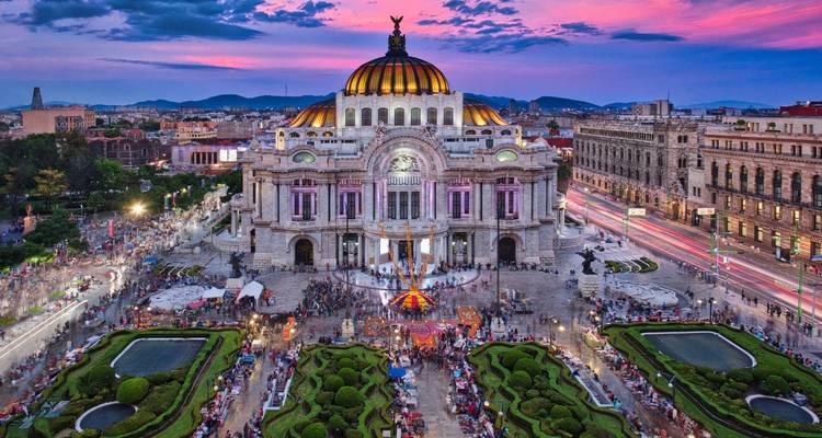 Vue aérienne nocturne du Palacio de Bellas Artes à Mexico avec un ciel de coucher de soleil coloré, des foules animées, des traînées lumineuses et des jardins paysagers.