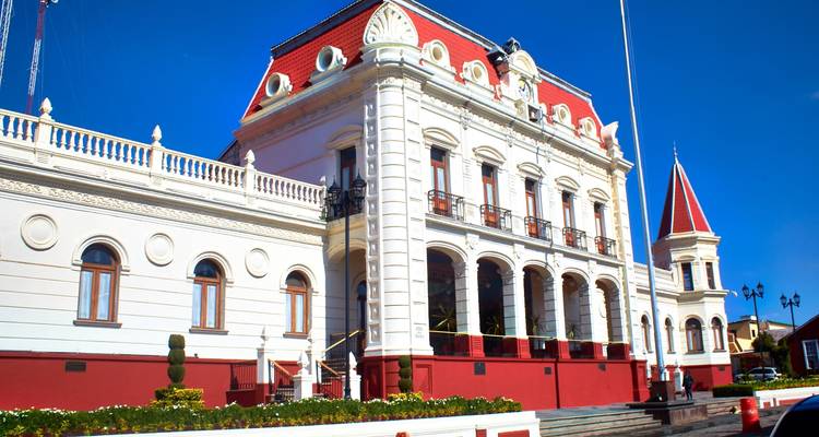 Bâtiment municipal néoclassique blanc avec des accents de toit rouge se dressant éclatant contre un ciel bleu vif.