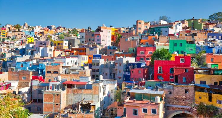 Patchwork vibrant de maisons multicolores empilées sur les flancs de collines de Guanajuato sous un ciel dégagé.