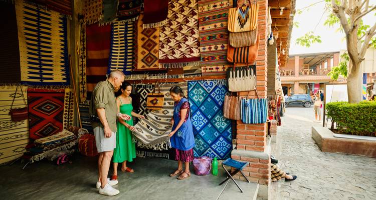 Des gens parcourant des textiles dans un marché traditionnel.