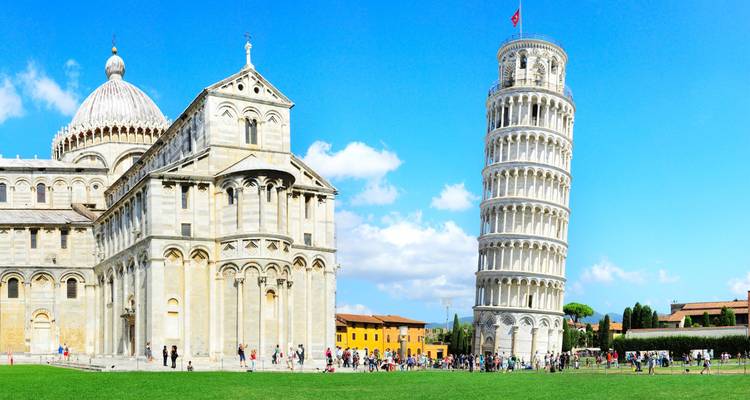 Iconic Leaning Tower and Pisa Cathedral standing over a green lawn bustling with tourists on a sunny day.