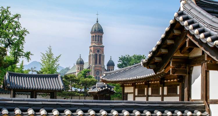 Arquitectura tradicional coreana con una iglesia al fondo.