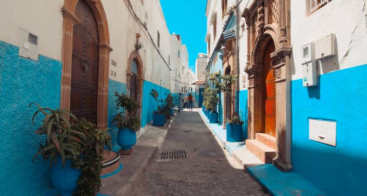 Rue piétonne étroite aux murs peints de bleu et blanc éclatants.