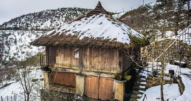 Grenier en bois au toit de chaume rustique dans la campagne montagneuse enneigée d'O Cebreiro.