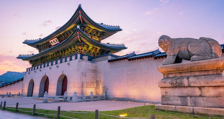 Entrée du palais Gyeongbokgung avec une statue de lion au coucher du soleil.