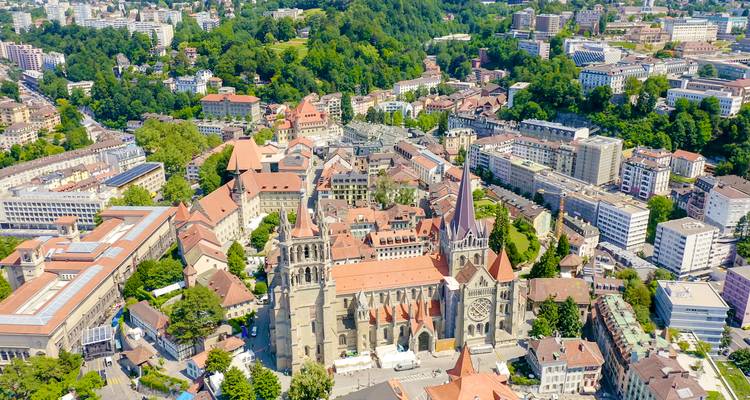 Vue aérienne de Lausanne avec des églises historiques et un paysage urbain vibrant.