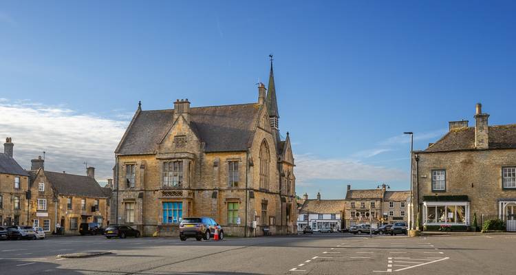 Steingebaute Marktplatzgebäude unter klarem Himmel in einer ruhigen Stadt in den Cotswolds.