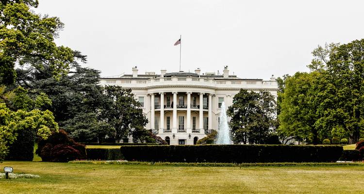La Maison Blanche avec des jardins luxuriants et un drapeau américain.