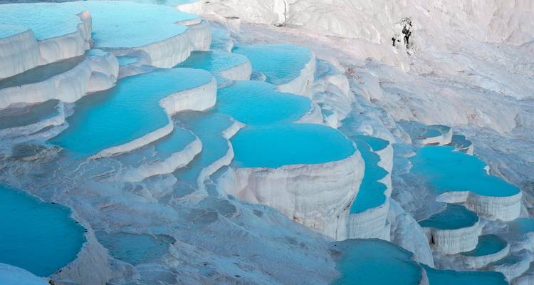 Vivid turquoise thermal terraces cascading down white limestone formations.