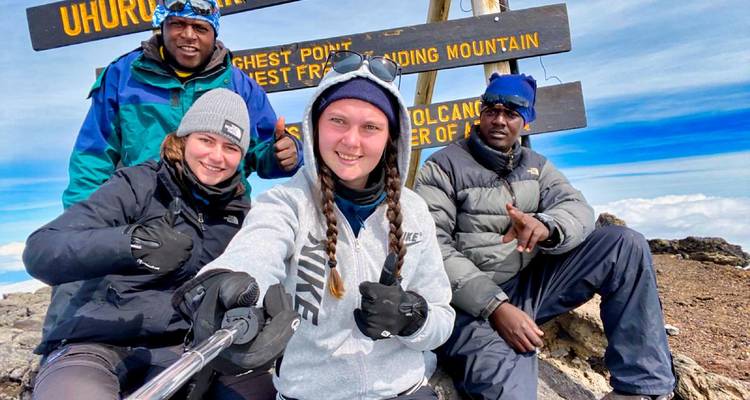 Groupe de personnes au sommet Uhuru avec un panneau