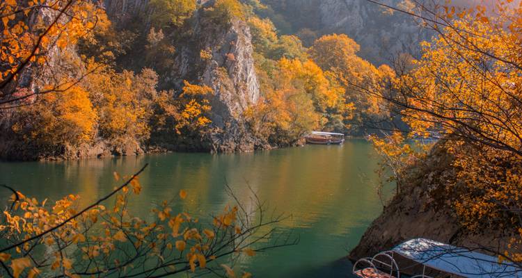 Vista panorámica del río con follaje otoñal y embarcaciones.