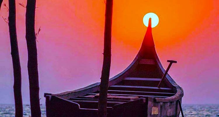 Un bateau traditionnel silhouetté contre un coucher de soleil rouge vibrant sur une plage.