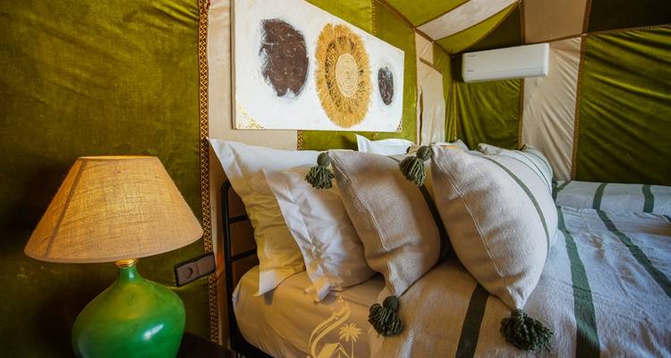 Gros plan d'un lit avec des oreillers décoratifs dans une tente.