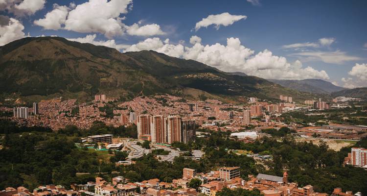 Paysage urbain avec des montagnes en arrière-plan sous un ciel bleu.
