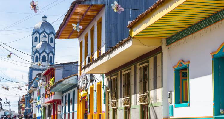 Rue colorée avec une architecture unique et un clocher d'église.
