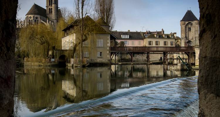 Maisons historiques au bord d'une rivière avec une petite cascade.