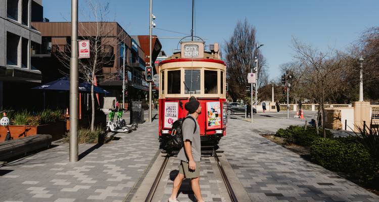 Personne marchant vers un tramway historique de la ville dans un environnement urbain.
