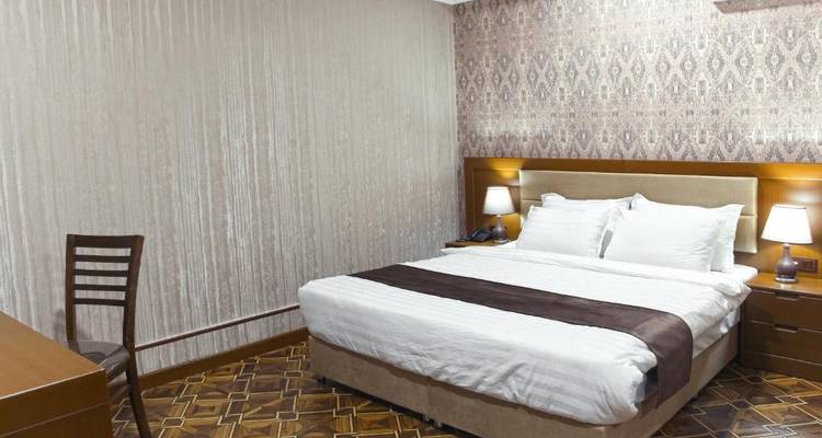 Una habitación de hotel con una cama con un patrón decorativo y un escritorio de trabajo.