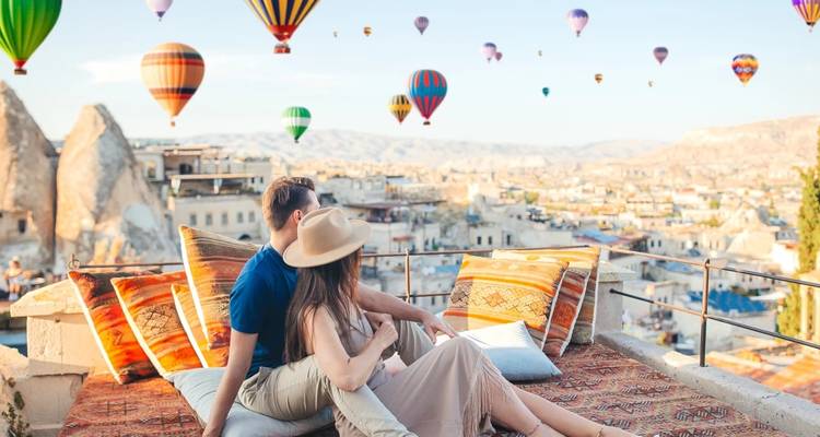 Couple assis sur une terrasse regardant des montgolfières en Cappadoce.