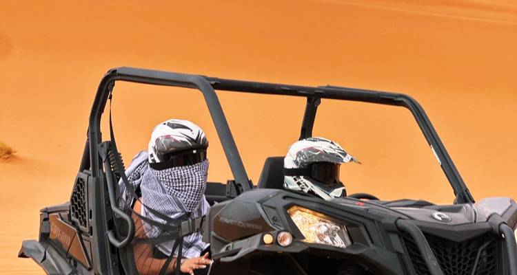 Deux personnes dans un véhicule tout-terrain traversant le désert.