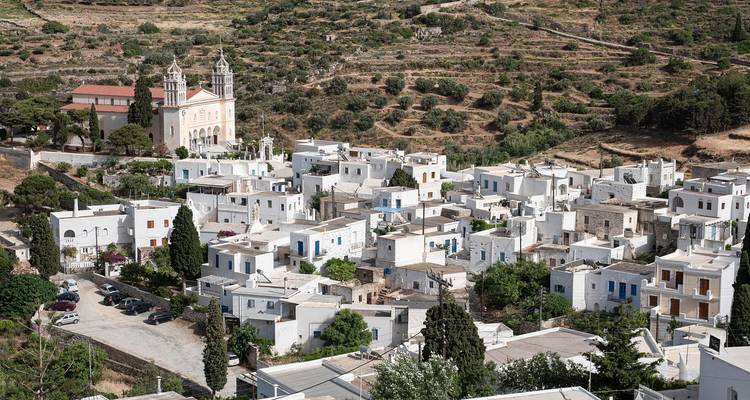 Luftaufnahme eines Dorfes mit weißen Häusern und einer Kirche, umgeben von hügeligem Gelände.