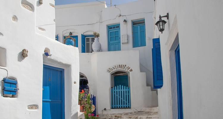 Weiße Häuser mit blauen Türen und Fenstern im traditionellen griechischen Inselstil unter einem klaren Himmel.
