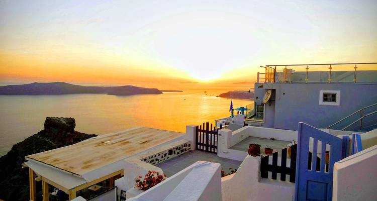 Sonnenuntergangsblick über eine Küstenlandschaft mit weißen Gebäuden auf Klippen.