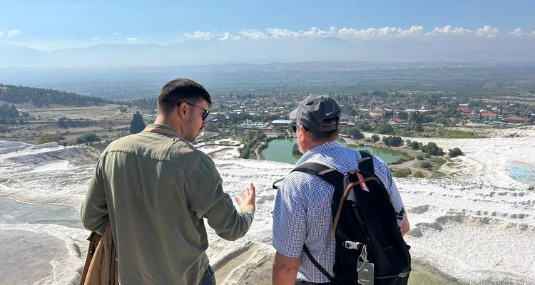 Two people overlooking a scenic landscape with pools in Pamukkale.