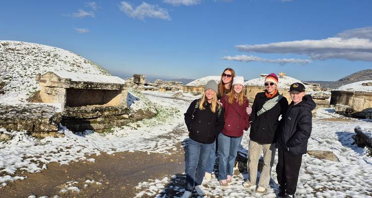 Group of people posing at an ancient site with snow on the ground.