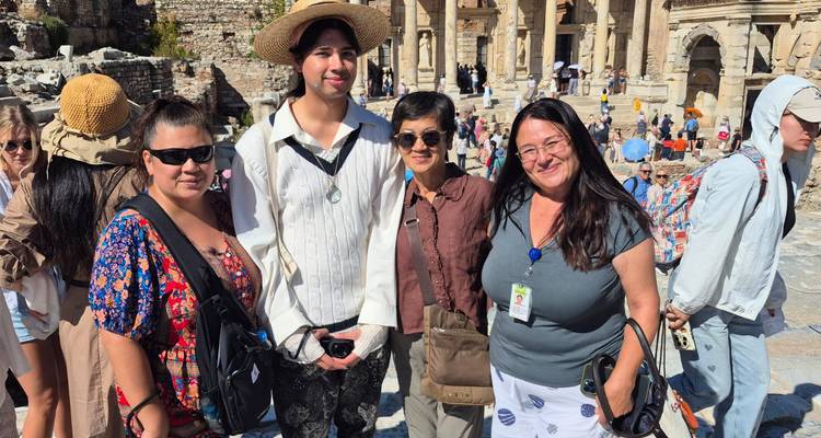 Group of people in front of ancient ruins with many tourists.