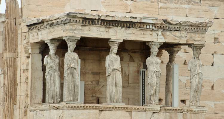 Structure ancienne avec des colonnes de pierre et des statues devant.