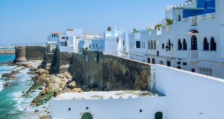 Witgekalkte Atlantische vestingwerken en huizen gelegen boven rotsachtige kustlijn in Asilah