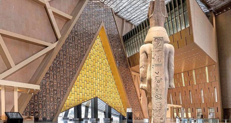 Innenraum des Großen Ägyptischen Museums mit antiker Statue und moderner Architektur.