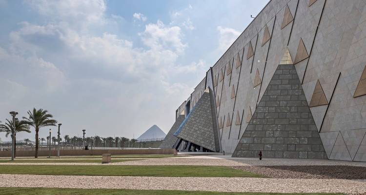 Außenansicht des Großen Ägyptischen Museums mit Pyramidenstrukturen unter einem bewölkten Himmel.