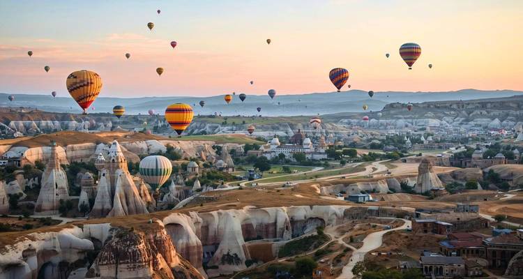 Hot air balloons over a rocky landscape at sunrise.