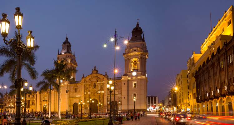 Place de la ville illuminée avec une cathédrale et des lampadaires la nuit.