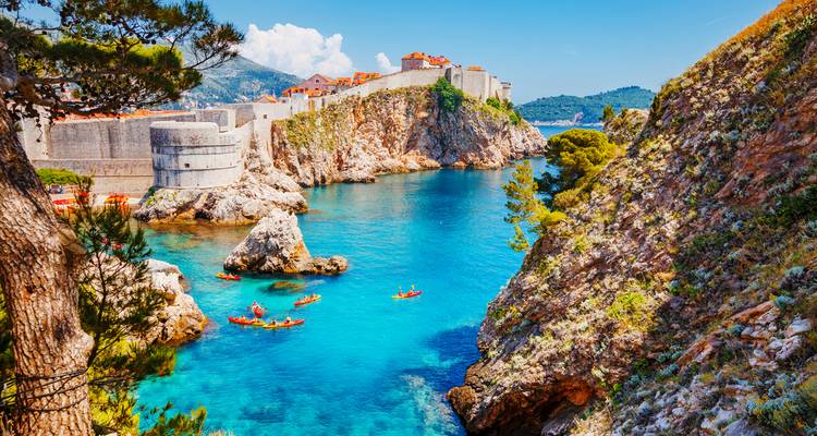 Eaux turquoise avec des kayakistes sous les anciens murs de pierre et fortifications de Dubrovnik.