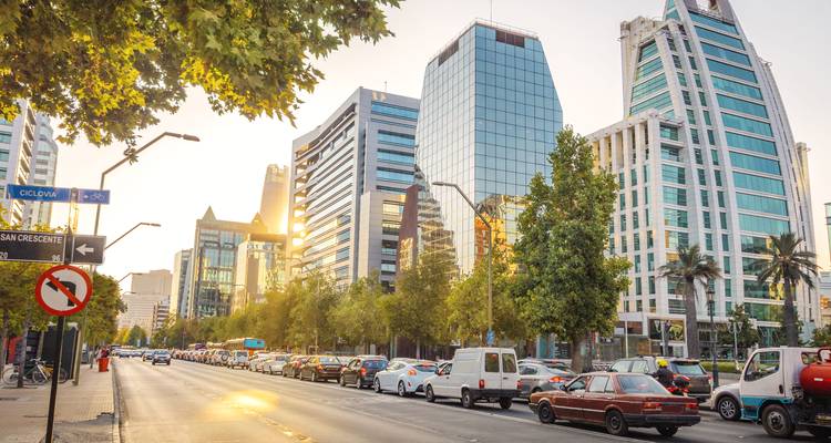 Calle de la ciudad con edificios modernos y tráfico al atardecer.